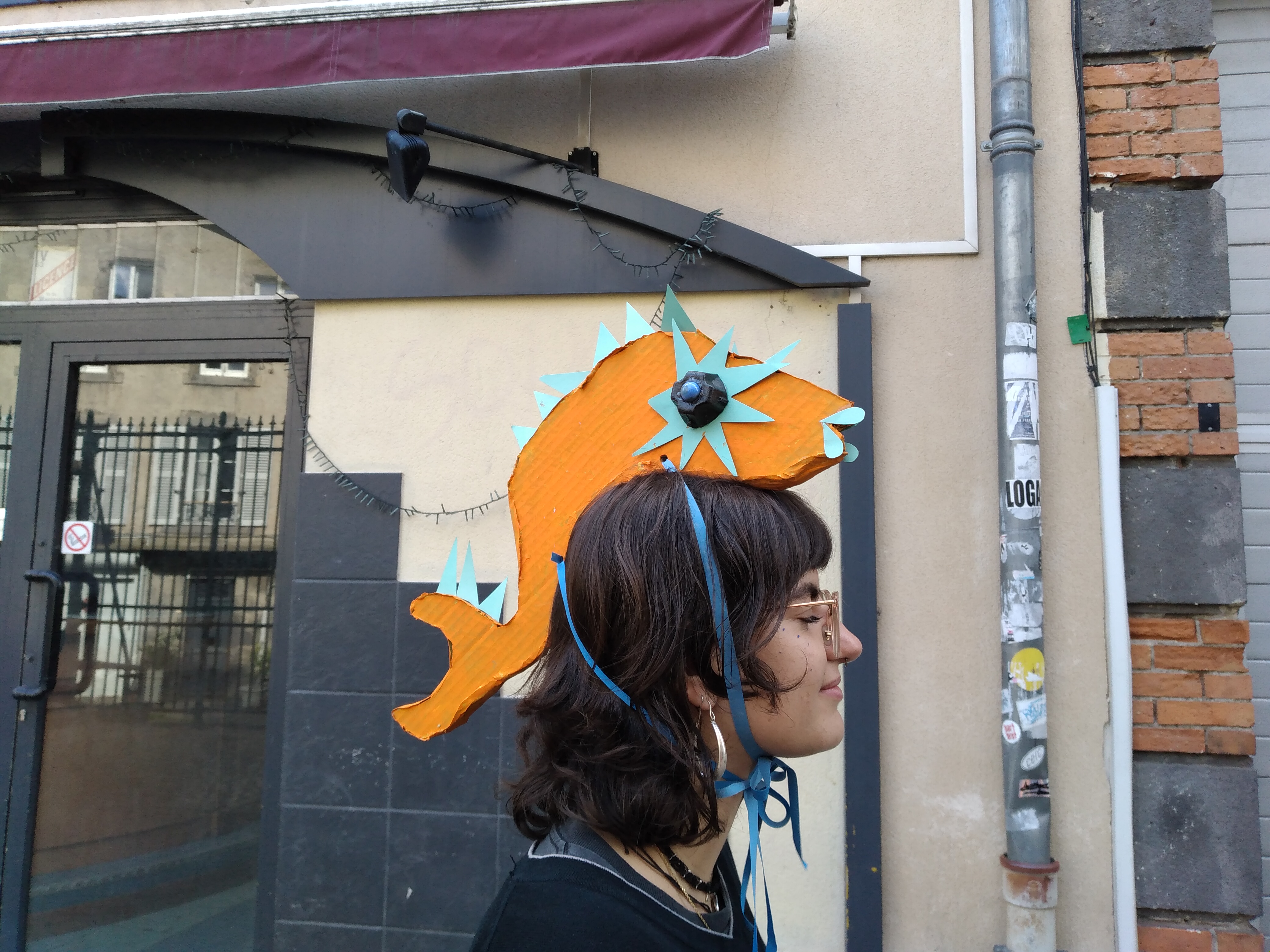 Poisson orange et nageoires bleu ciel perché sur la tête d'une personne aux cheveux noirs.