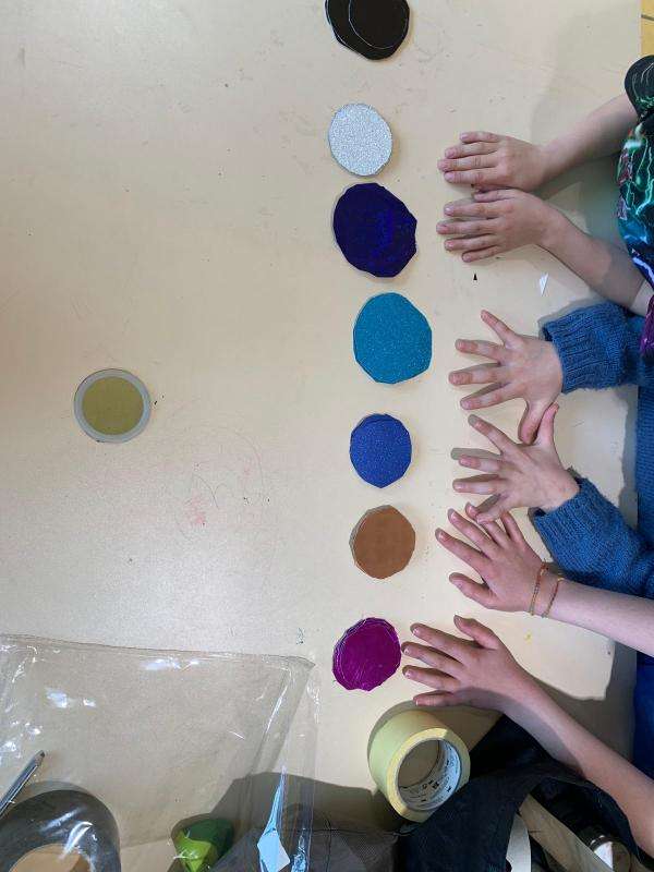 mains et cartons ronds peints en bleus, rouge, blanc, jaune