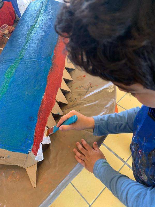 Un enfant peint les dents blanches de la dragonne d'eau
